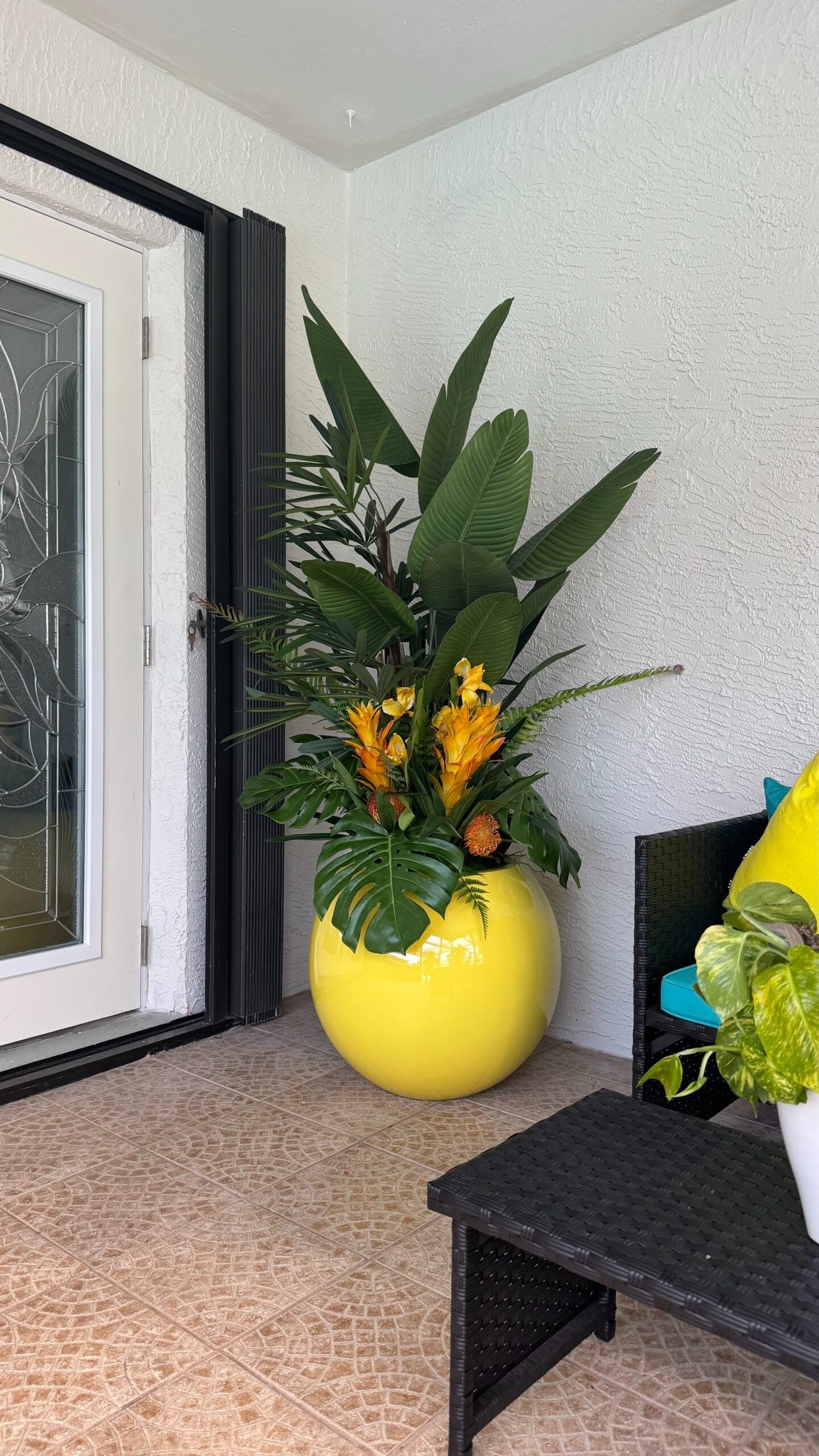 Tropische Mix-Dekoration in einem gelben runden Pflanzgefäß