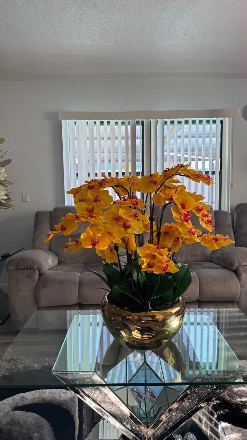 Kaskadierende gelbe Orchideen in einer goldfarbenen Edelstahlvase