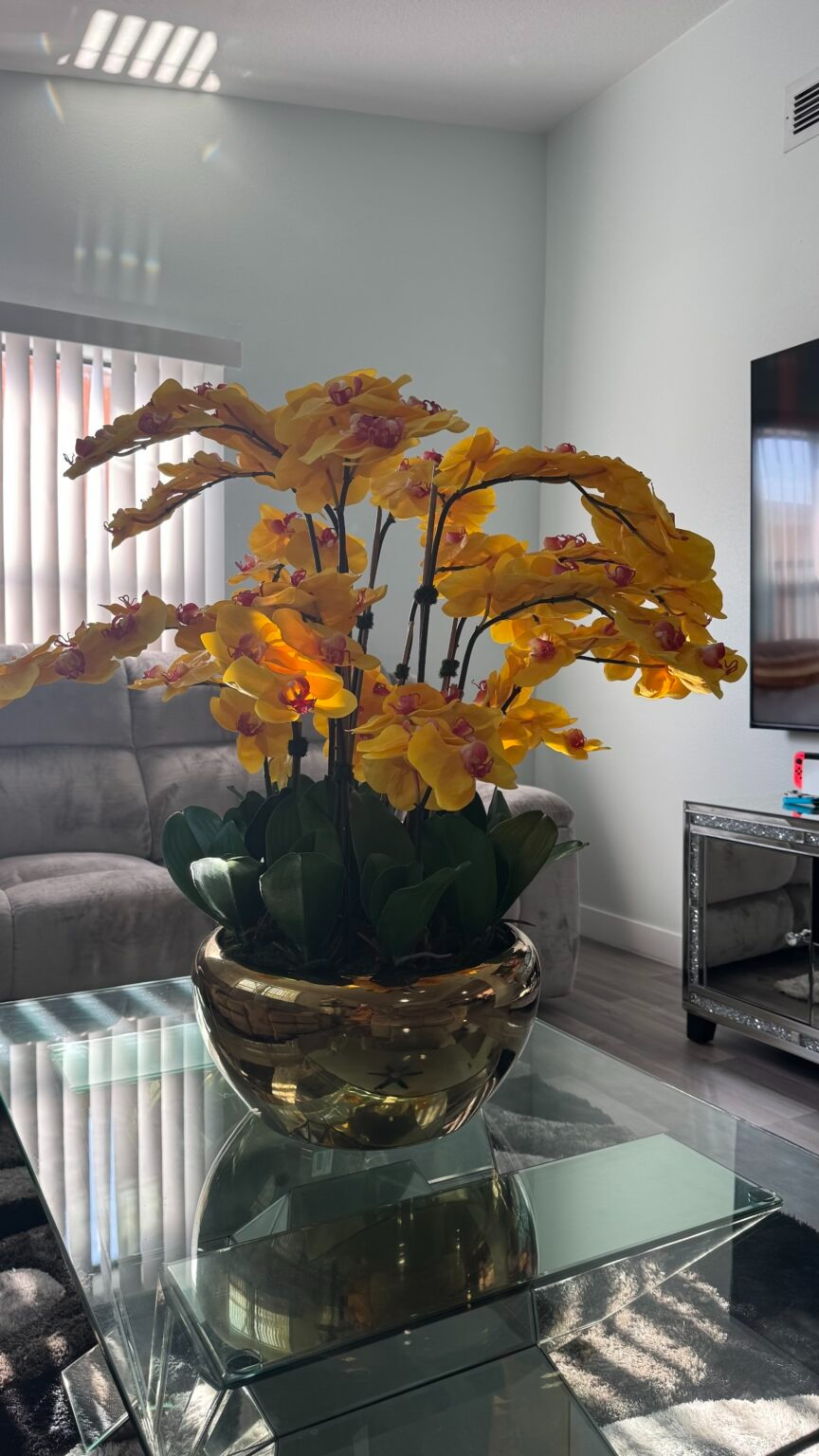 Kaskadierende gelbe Orchideen in einer goldfarbenen Edelstahlvase